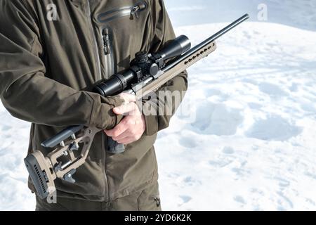 A sniper rifles from a rifle with an optical sight in man`s hands stands winter day Stock Photo